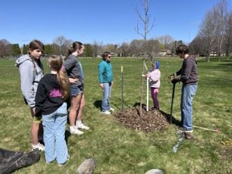 People standing around a tree after it was planted. 